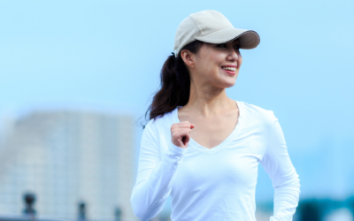 AAPI woman in light blue top and white hat walking and smiling